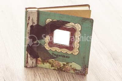 A aged photo album sits on a rustic wooden background