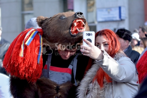 A man dressed as a bear and a young woman takes her own photo.