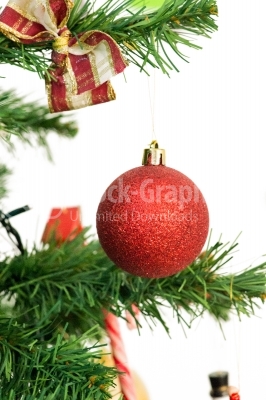 A red matted glass christmas ornament hanging from a xmas tree