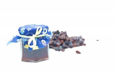 Big dark raisins in glass jar on a white background