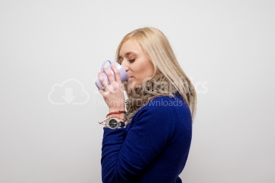 Blond girl drinking coffee or tea and smiling