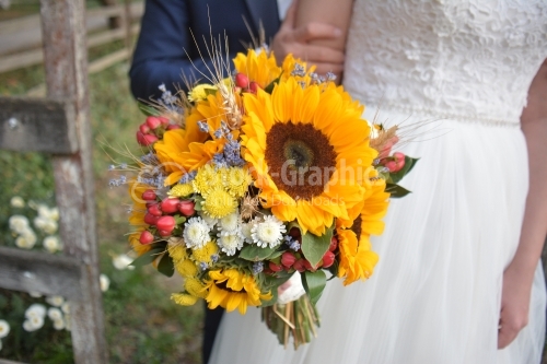 Bride and groom and a bouquet of flowers in hand, the bouquet has summer flowers especially sunflower.