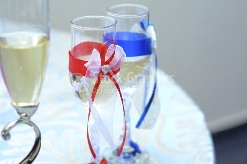 Champagne glasses with blue and red representing the bride and g