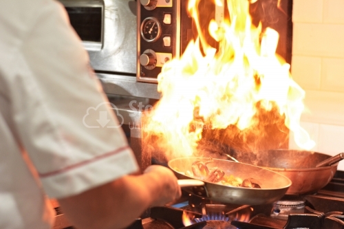 Chef cooking with flame. Restaurant kitchen. Hotel.