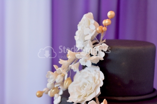 Close-up view wedding cake. Bouquet of beige flowers on cake with black marzipan