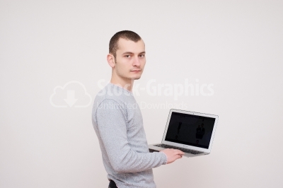 Confident young man with laptop standing over white background. 