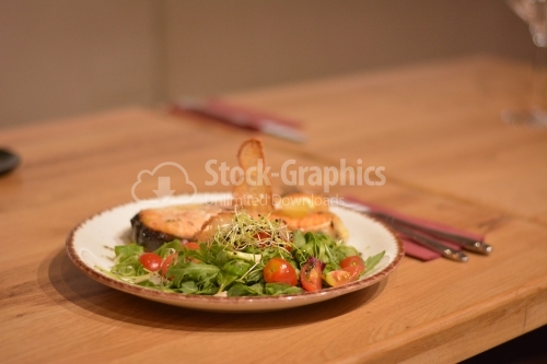 Fried fish with salad. The salad contains tomatoes, valerian, wheat germ and lettuce.