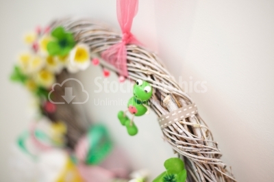 Funny frog sitting on a spring wreath