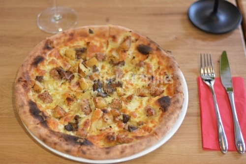 Hawaiian pizza with pineapple on rustic wooden background.
