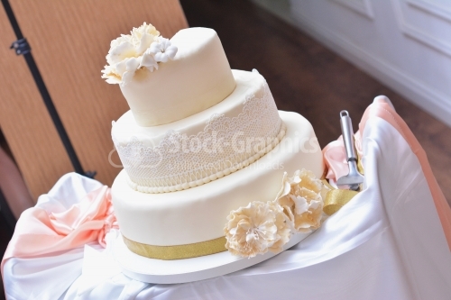 Ivory cake decorated with ivory flowers and white lace