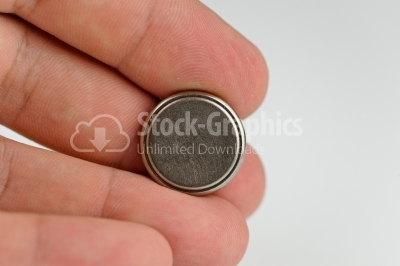 Lithium button cell in hand - Stock Image