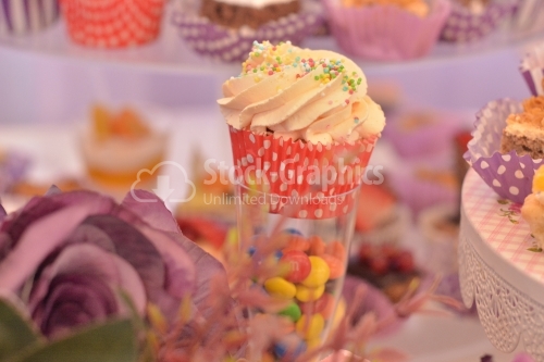 Muffin with whipped cream and rainbow candy. Candy bar