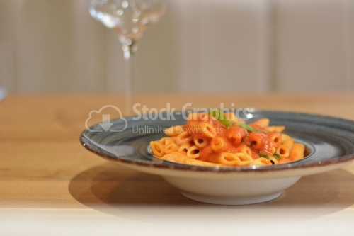 Penne pasta with red sauce and basil in a gray plate.