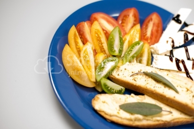 Plate arangement - Fresh tomatoes, chees and bread on a blue pla