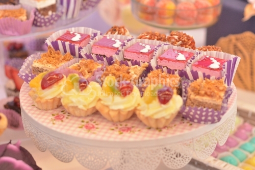 Plate with assorted cakes: cream and strawberry jelly cakes, walnut and crunchy caramel cake and vanilla cream mini tarts
