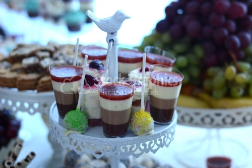 Pudding in layers with cocoa, strawberries, whipped cream, cappuccino and fruit combined with fondant on a stick
