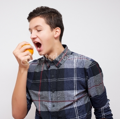 Smiling young man biting an orange
