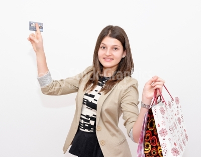 Smiling young woman with a credit card in a hand and shopping ba