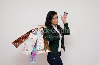 Smiling young woman with a credit card in a hand and shopping ba