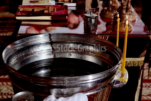 The baptismal font with candles and a table with icons and a cross in the church.
