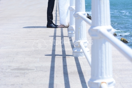 The feet of the groom and the bride on a walkway at sea.
