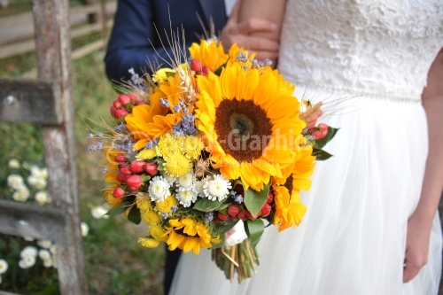 The groom, the bride and a bouquet of flowers. The sunflower is part of the wedding theme.