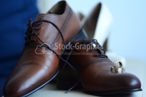 The groom's brown shoes and engraved gold wedding rings.