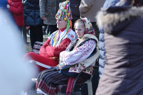 Two tired young people, dressed in romanian national costume at the winter festival. Authentic traditional from Romania