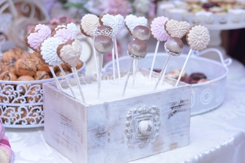 Various cake pops decorated with white and dark chocolate on a white-pink background