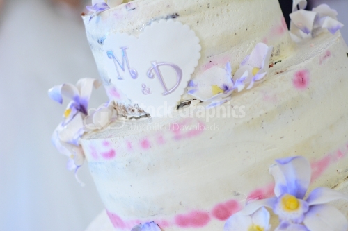 Wedding cake with white-purple flowers and the initials of letters M and D