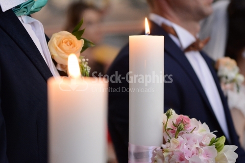 Wedding candles decorated with flowers. Silhouettes of men in the background.