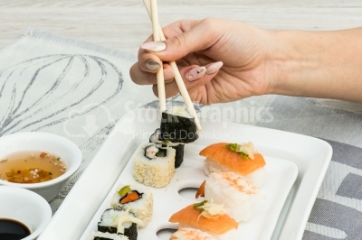Woman hand arranging sushi on plate
