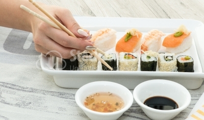 Woman hand arranging sushi rolls